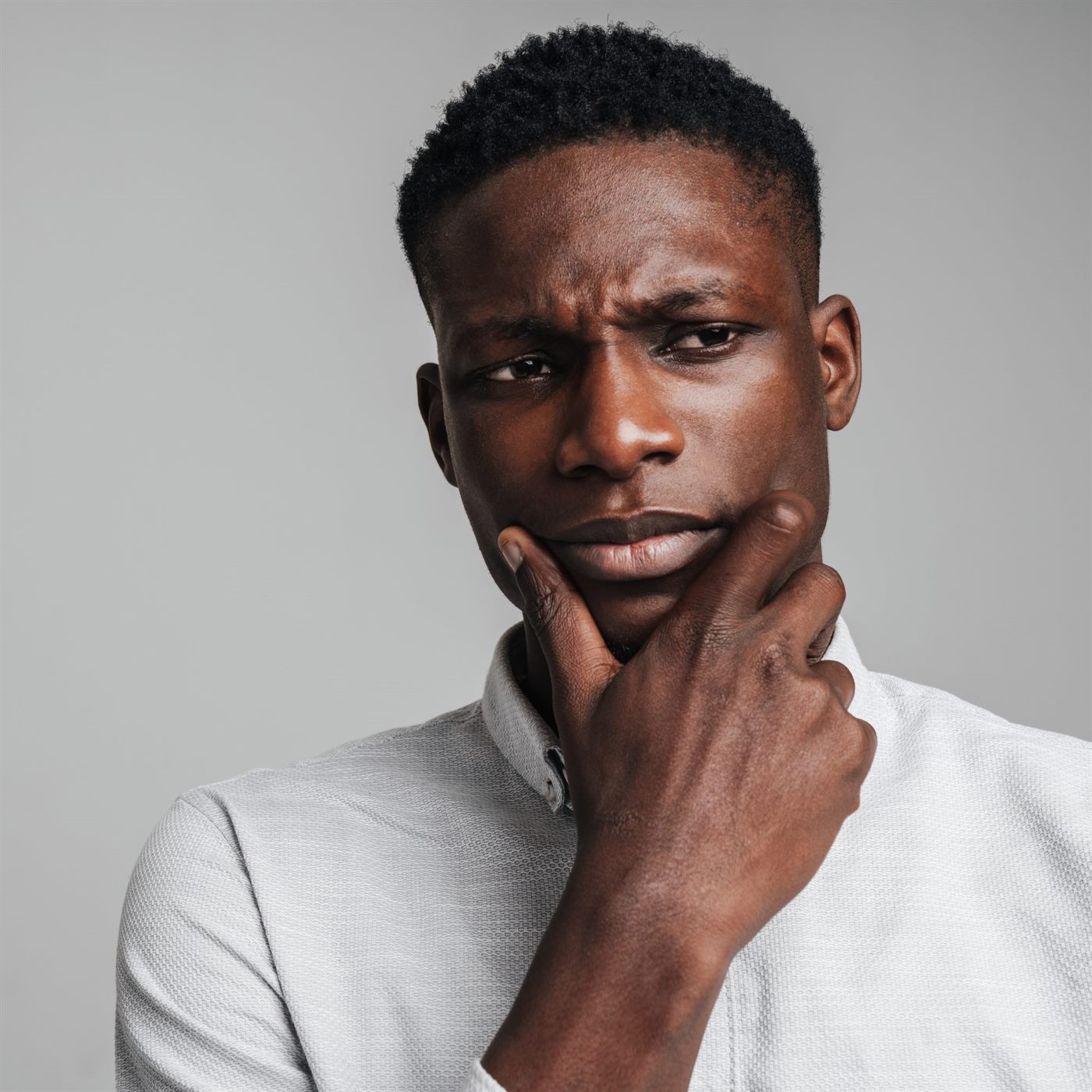 A young man resting his chin on his hand, thinking