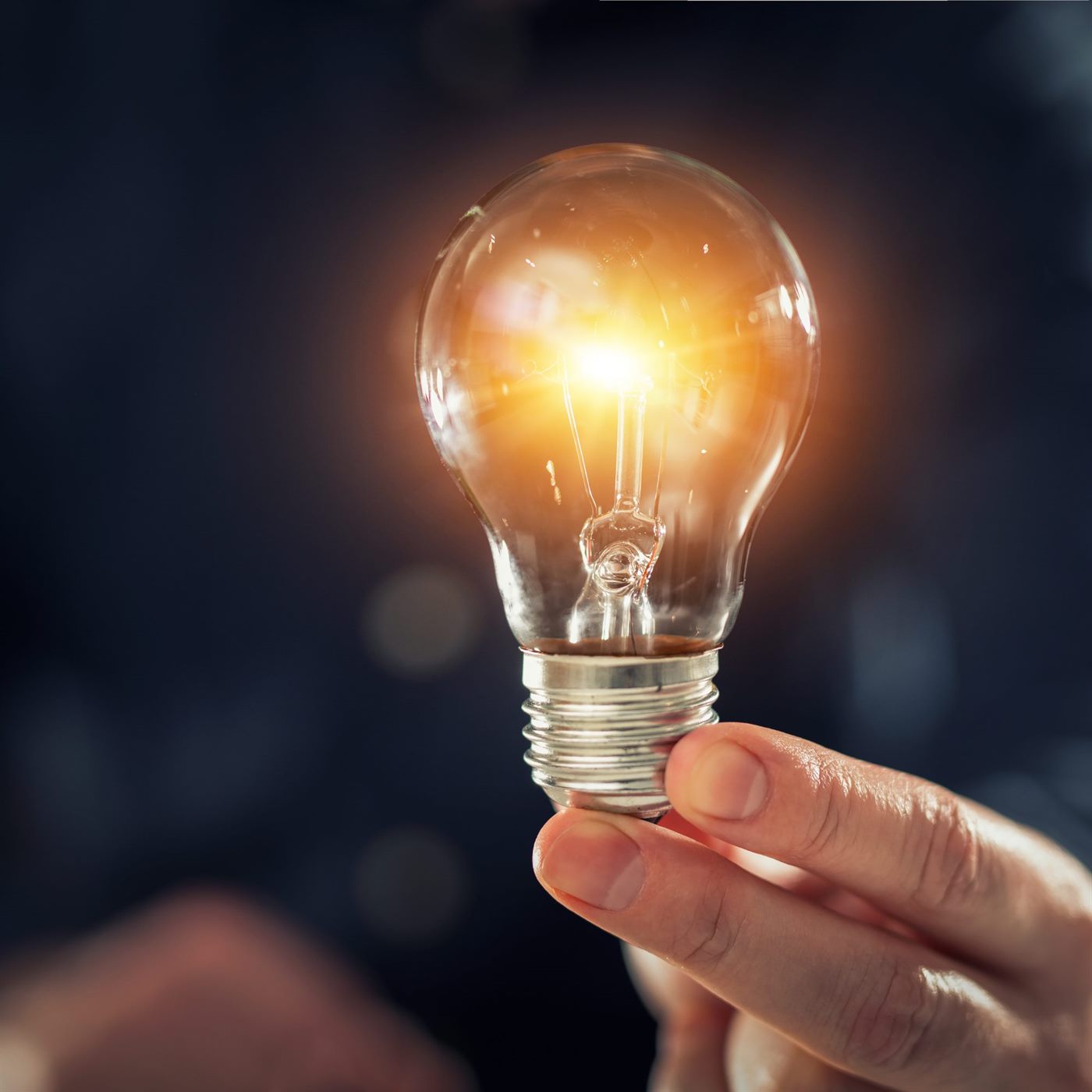 A glowing lightbulb resting in an open hand